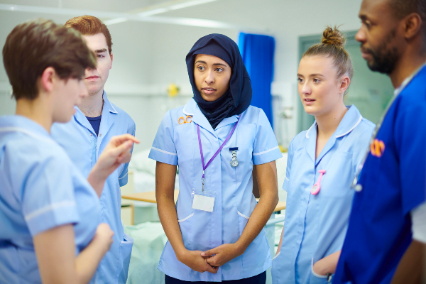 تعدادی پرستار دختر و پسر در حال صحبت کردن در محیط بیمارستانی در انگلیس هستند - تحصیل پرستاری در انگلستان